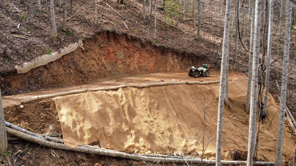 Aerial drone view of site preparation, excavation equipment, and winding road network